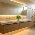 Salle de bain moderne avec double vasque, plan en marbre, meubles en bois et éclairage LED chaleureux.
