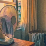 Comment rafraîchir une pièce avec un ventilateur : ventilateur sur table devant fenêtre